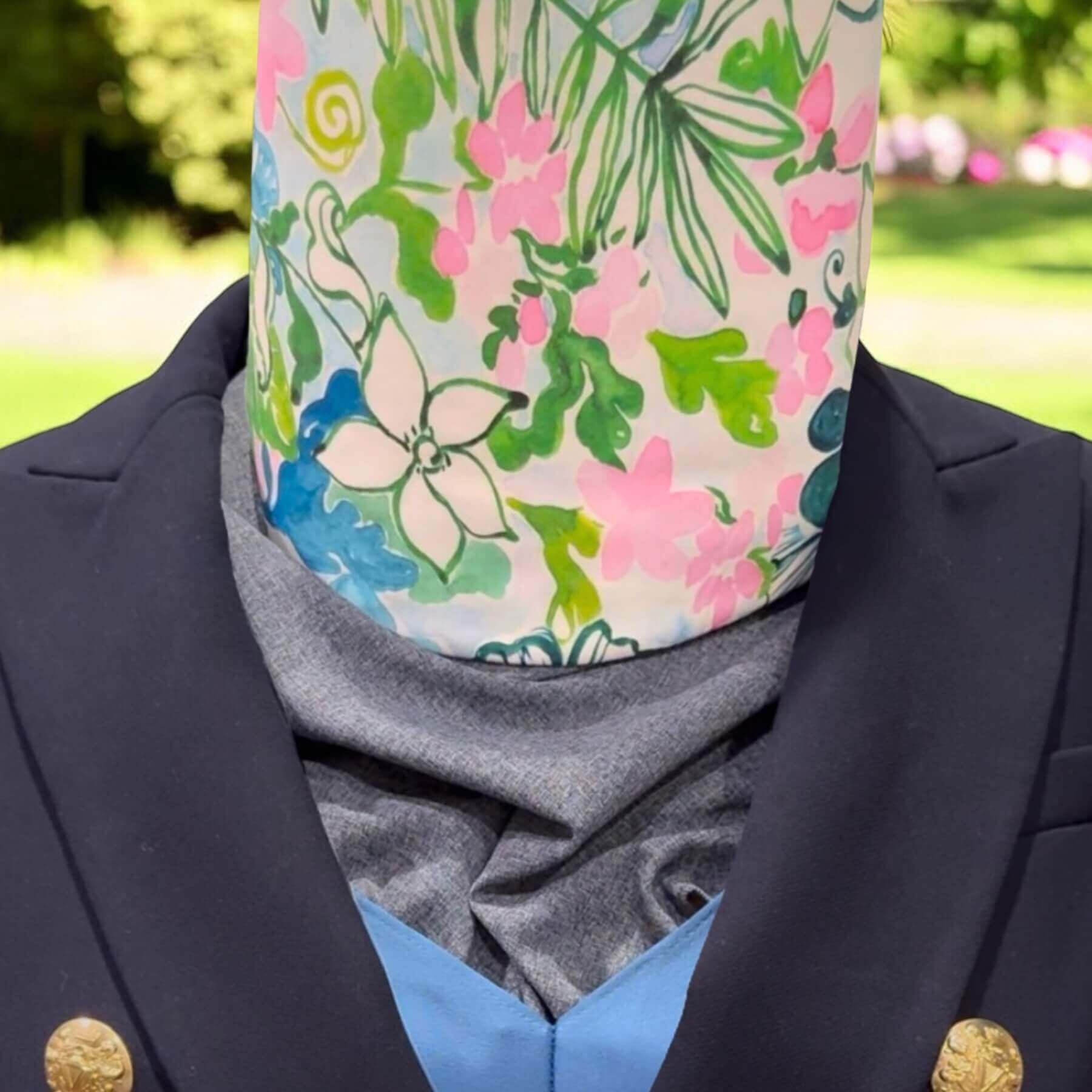 Functional Sun Dickey neck cover for sun protection shown with blue blazer in background out of focus is backyard with shrubs and flowers