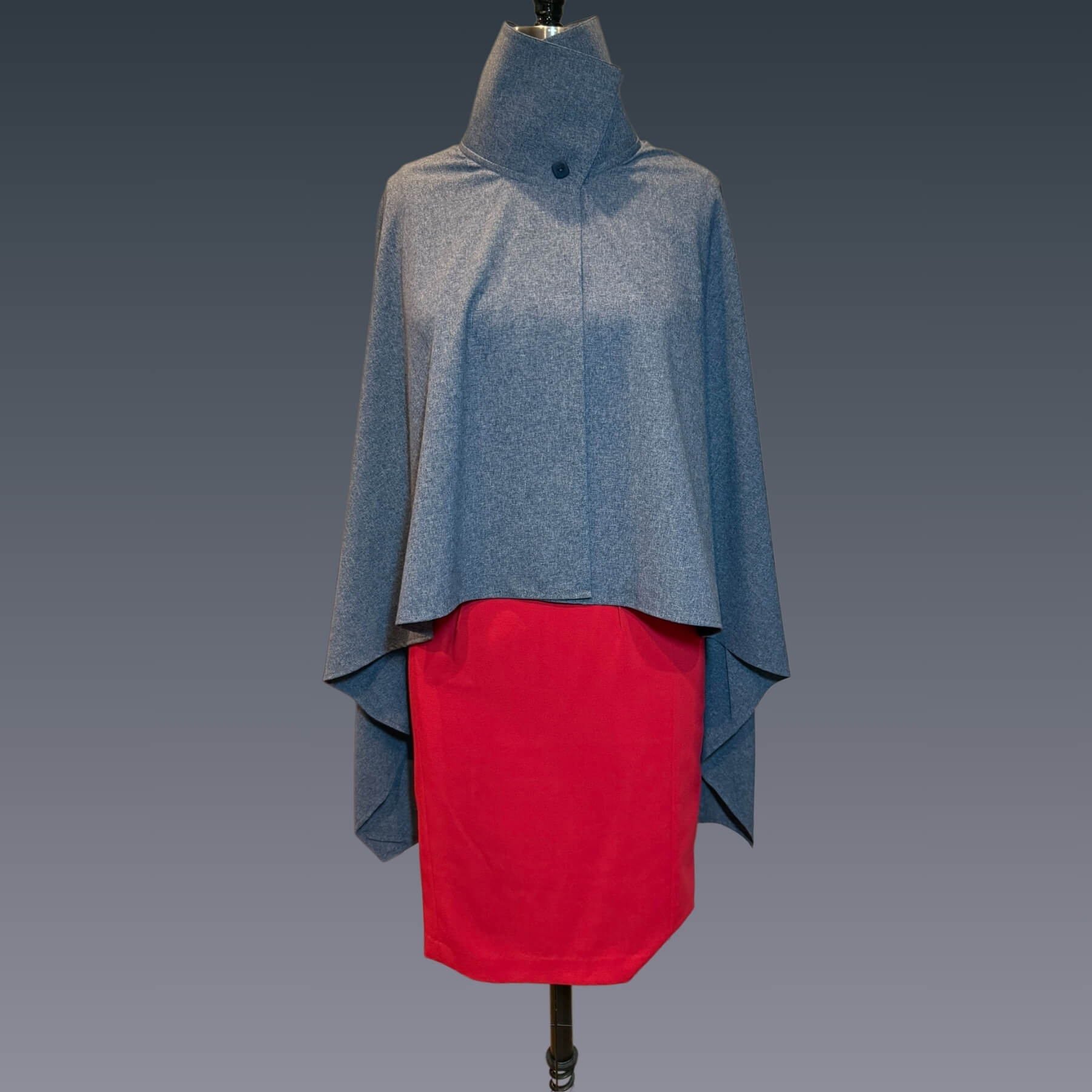 Front view of the Blue Melange Sun Wrap in UPF 50+ fabric, shown buttoned at the collar for versatile styling. Displayed on mannequin with red dress against a blue gradient background.