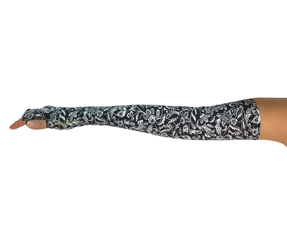 Heliades UPF 50 Sun Protective Clothing UV Arm Sleeves in fashionable, elegant allover navy blue and white floral print. UV covered arm and hand shown with bright green logo trim.