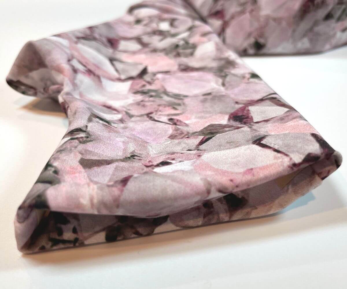 Heliades UPF 50 Sun Protective Clothing UV arm sleeves on printed fabric. Shown is fashionable, elegant allover pink, lavender, white, magenta print top of glove opening for fingers