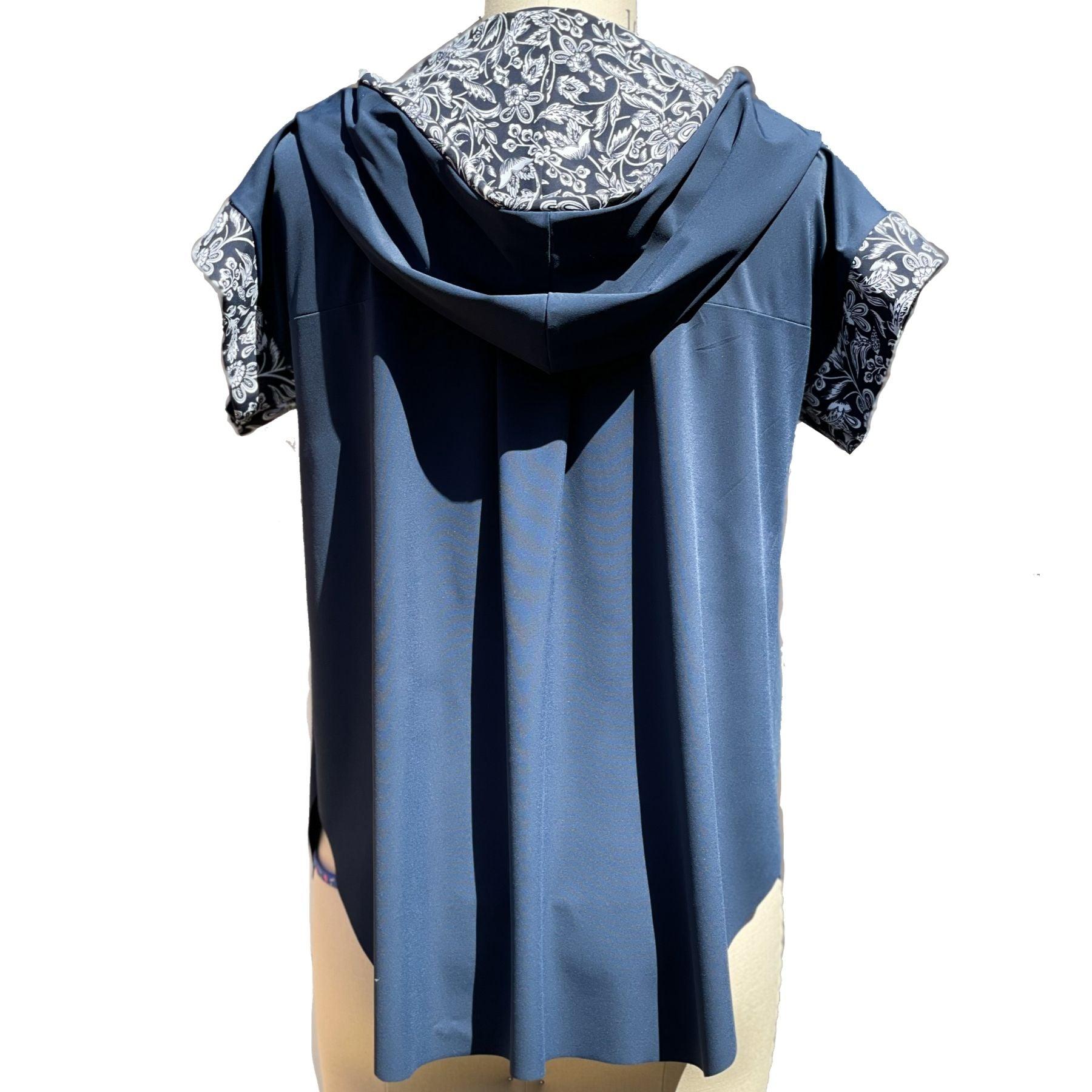 Back view of a short sleeved, UPF 50+ hoodie pullover tunic on a mannequin. The hoodie is true navy blue and the sleeves & inside of the hoodie are all sewn in a navy with white floral print. The Hoodie is long, loose and flowing like a tunic with split vents at the hips and a longer length in back for more rear coverage