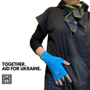 Woman’s torso shown wearing black and charcoal gray UPF50+ hoodie. On neck is UPF50+ sun protective scarf in reversible chartreuse and charcoal gray repeating rosette print, tied as a stylish cravat. On hands are UPF50+ sun protective gloves in Bright Blue Mood color. All fabric is OEKO-TEX certified. Words say Together. Humanitarian Aid For Ukraine. You purchase a pair of blue gloves, HELIADES will donate $75 towards aid for Ukraine.