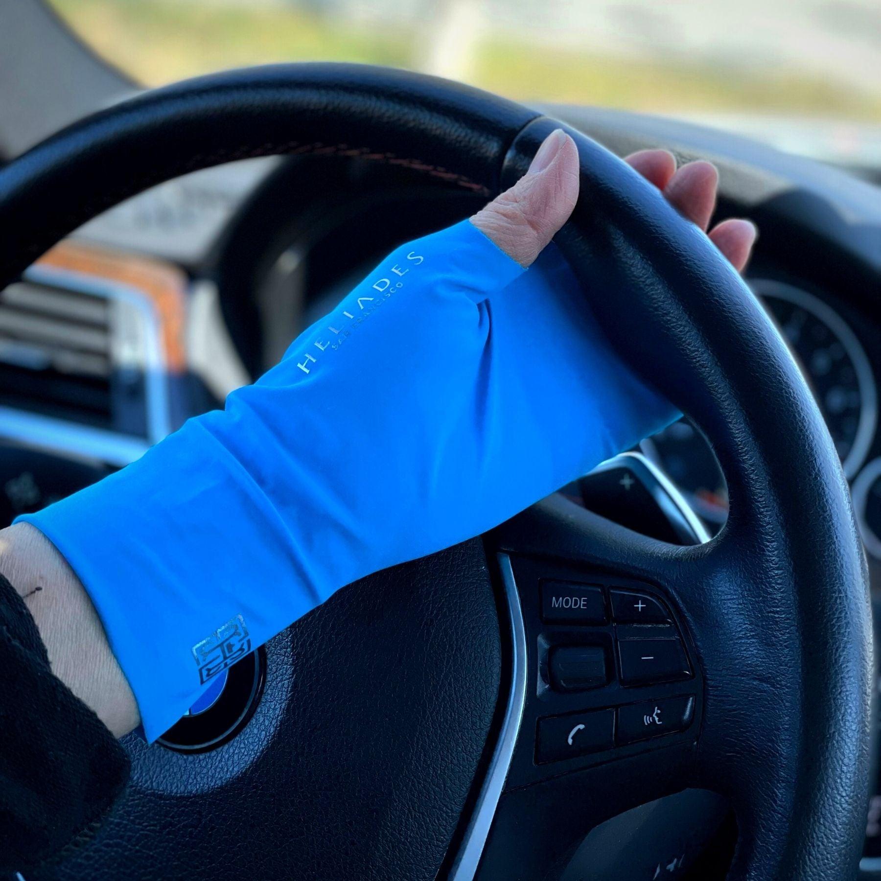 HELIADES UPF50+ sun protective fingerless, tagless gloves in Bright Blue Mood color with pink metallic logos on driving wheel. All fabric 98% UV blocking and OEKO-TEX certified.