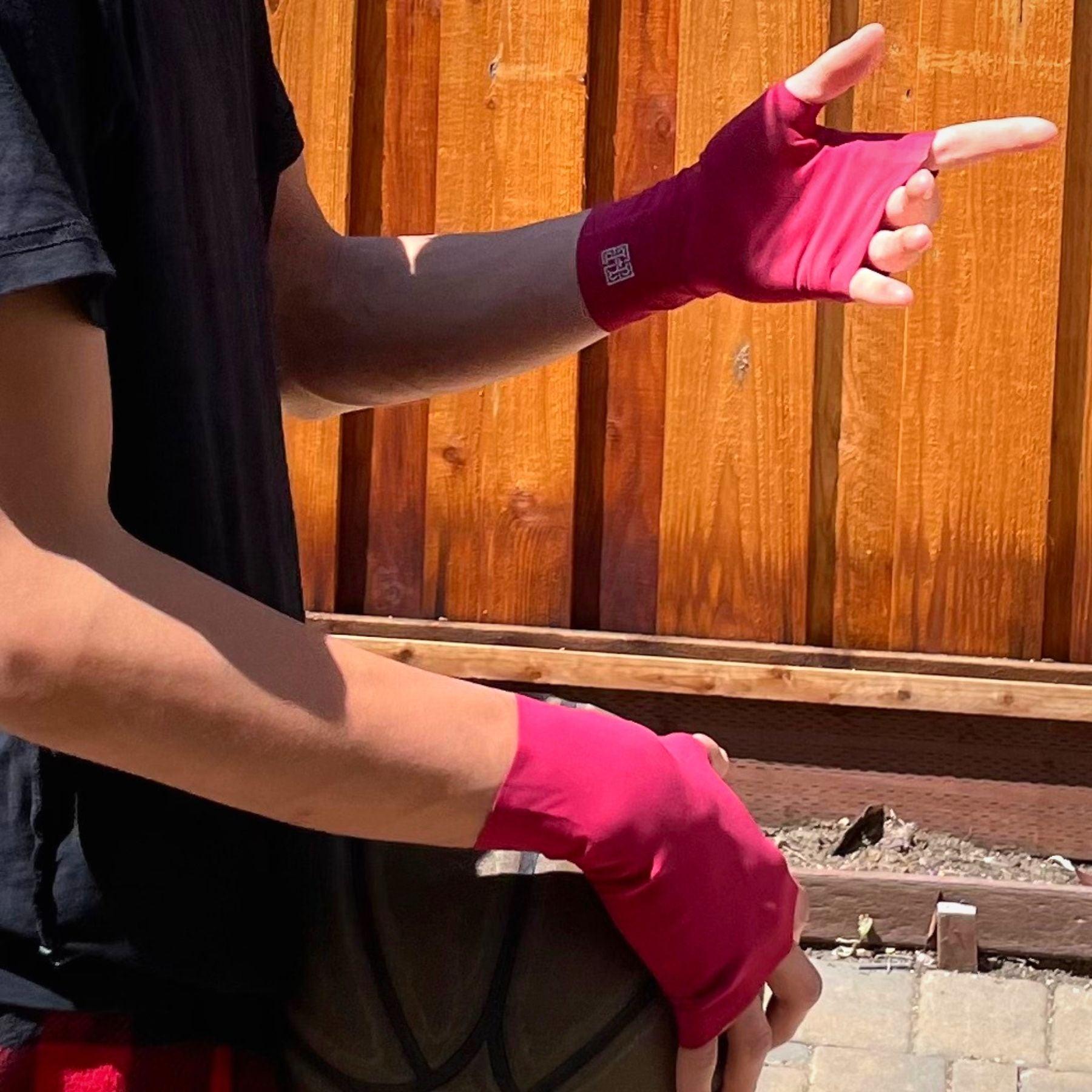 young man's hands holding a basketball, on hands are unisex UPF 50+ fingerless sun protection gloves in deep red color with silver reflective logos