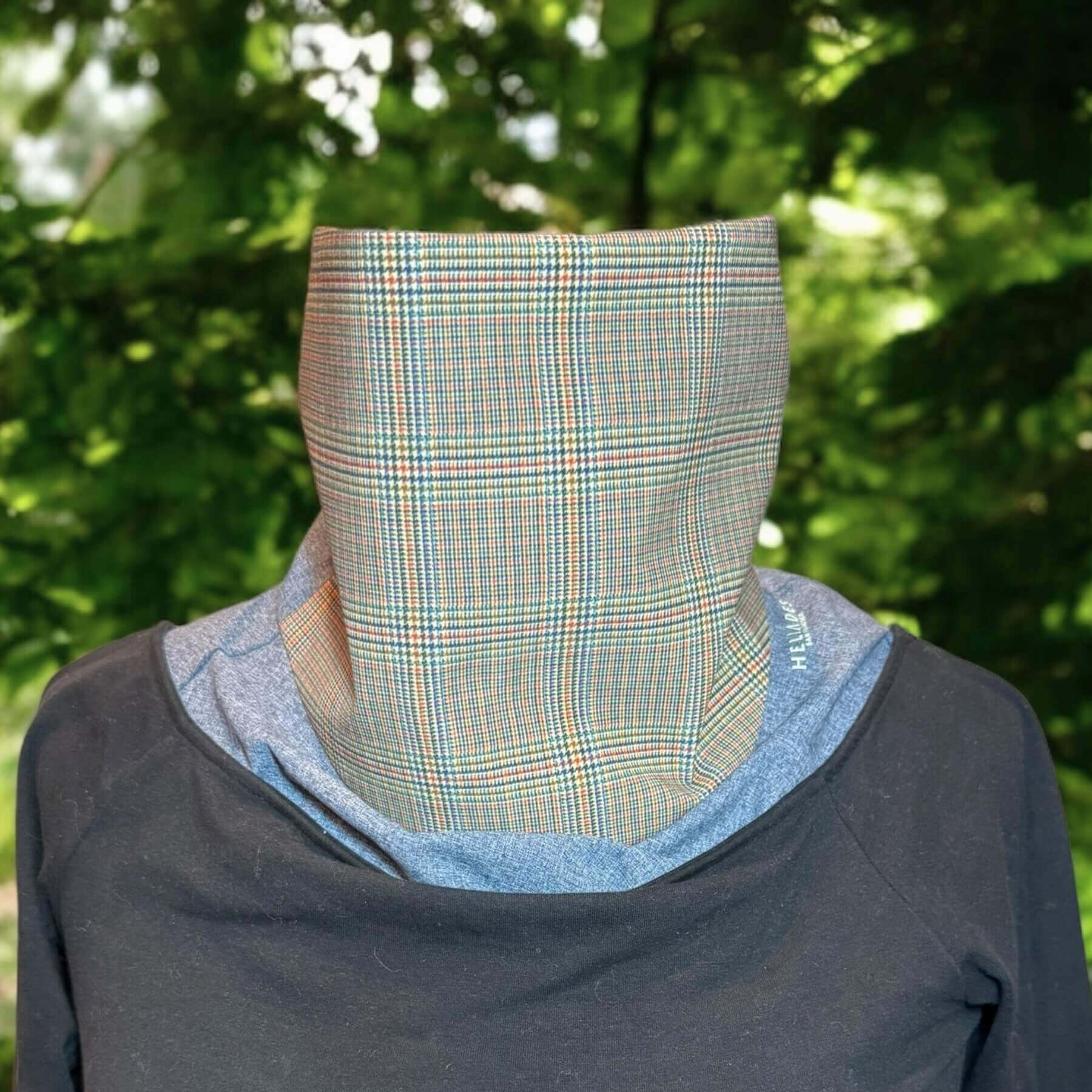 Fashion Sun Dickey shown on a mannequin in blue melange with classic glenn plaid print in shades of yellow, blue, orange and green is paired with a portrait collar black top. In background is green leaves from tree.
