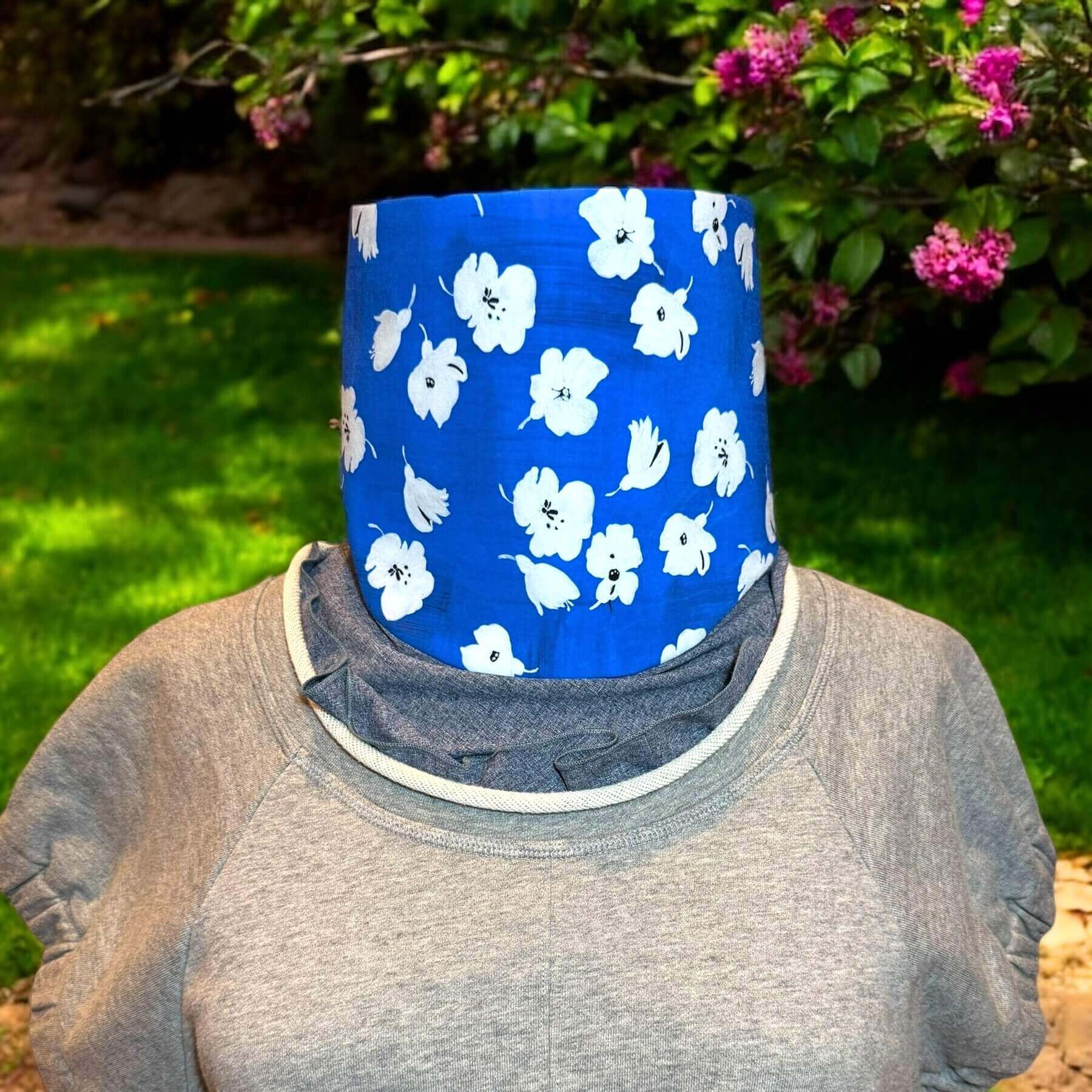 Heliades Sun Dickey shown paired with Philip Lim gray jewel collar sweatshirt. In background is backyard with grass, green shrubs and pink flowers.