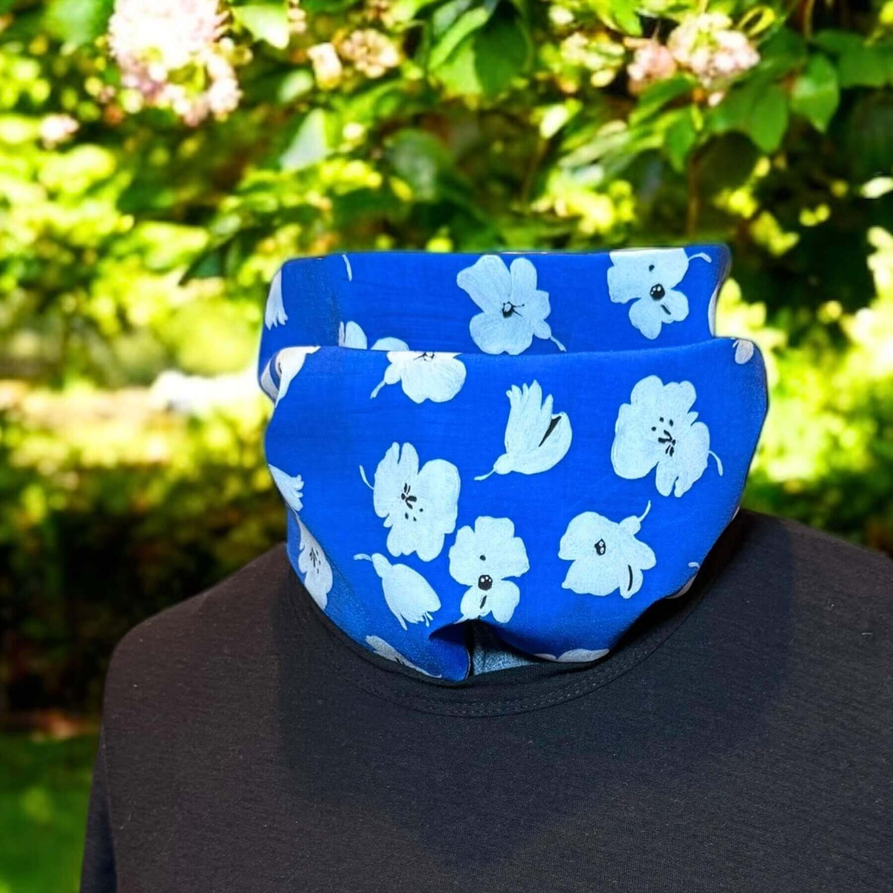 Fashion UV Sun Dickey shown with black James Perse t-shirt. In background is backyard with grass, green shrubs and pink flowers.