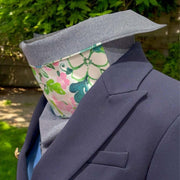 Side view of elegant Sun Dickey, collar turned down, paired with blue blazer. Backyard with shrubs, grass and dirt in background.