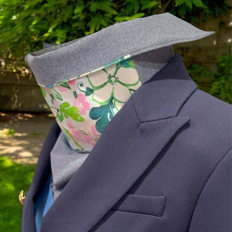 Side view of elegant Sun Dickey, collar turned down, paired with blue blazer. Backyard with shrubs, grass and dirt in background.