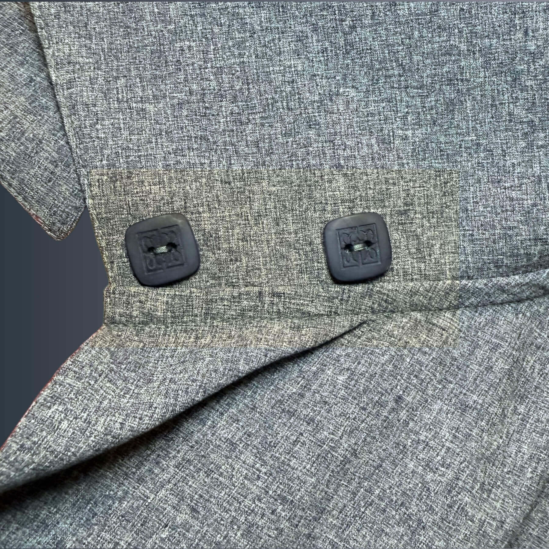 Close-up detail of the Blue Melange Sun Wrap in UPF 50+ fabric, showing two custom-dyed square buttons engraved with the Heliades logo on the collar, against a blue gradient background.