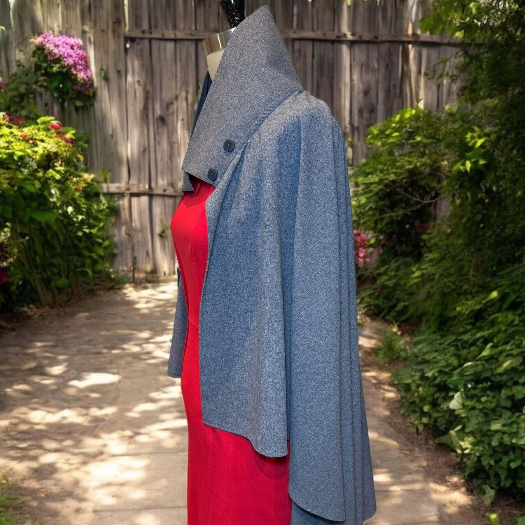 Side view of the Blue Melange Sun Wrap in lightweight UPF 50+ fabric, draped over the shoulders with fluid elegance. Shown on mannequin in red dress, backyard garden background.