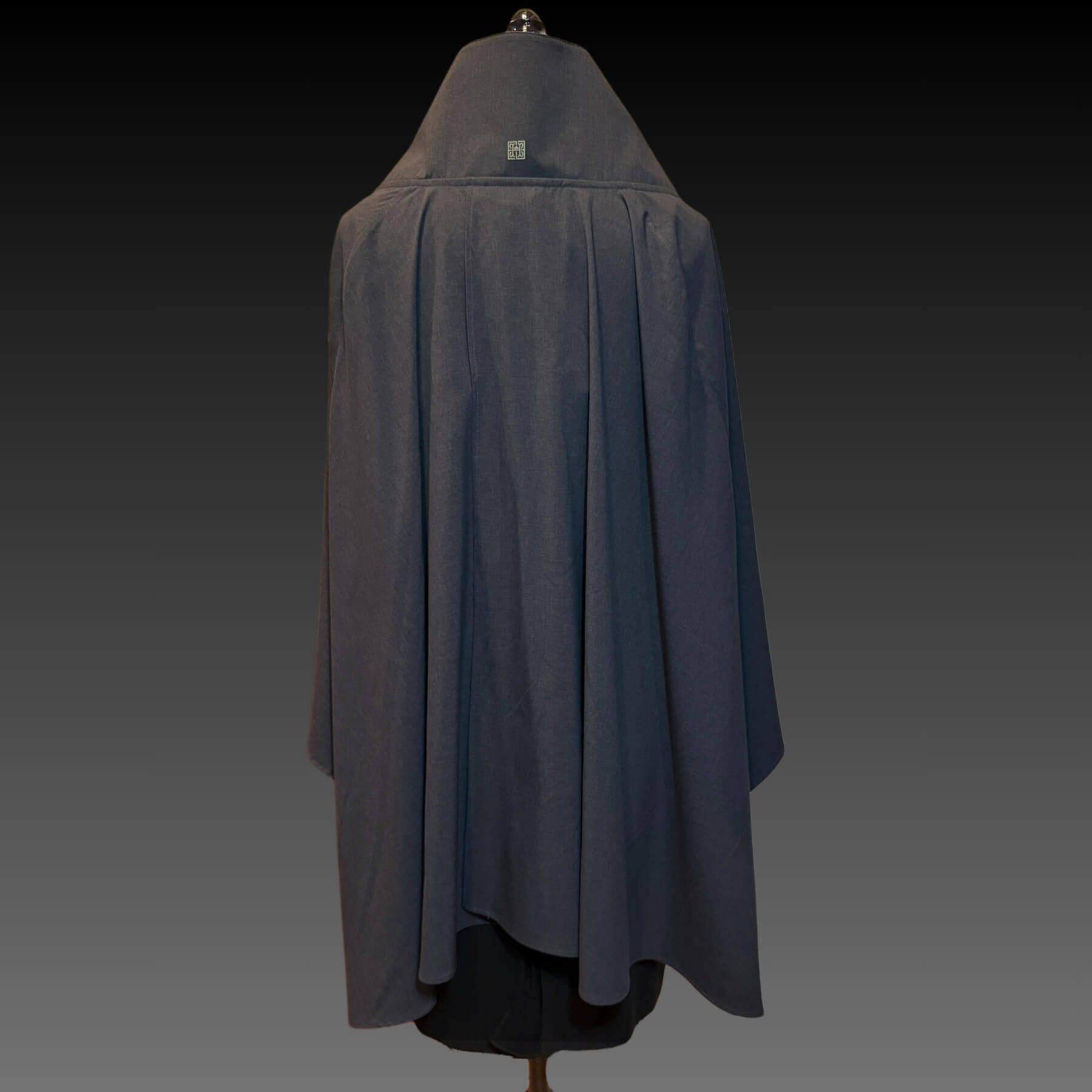 Back view of the Gray Melange Sun Shawl in UPF 50+ fabric, shown with collar up and gold logo trim. Displayed on mannequin against a black gradient background.