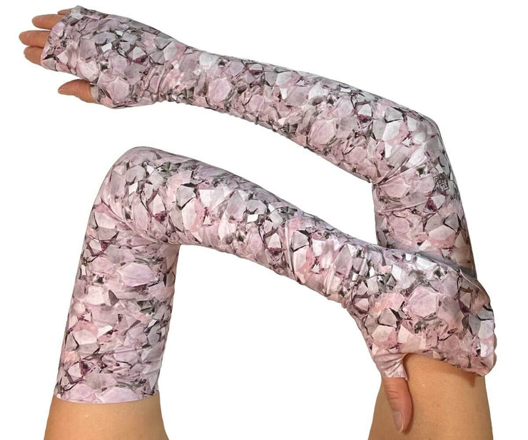 Heliades UPF 50 Sun Protective Clothing UV Arm Sleeves on printed fabric. Shown is fashionable, elegant allover pink, lavender, white, magenta print. UV sun covered arms and hands shown folded in front