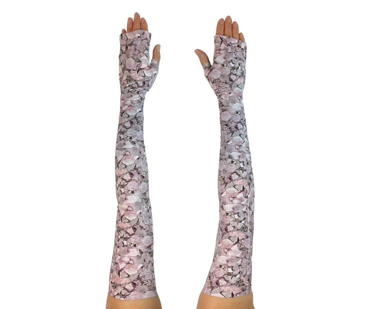 Heliades UPF 50 Sun Protective Clothing UV Arm Sleeves on stylish, printed fabric. Shown is fashionable, elegant allover pink, white, lavendar, magenta pattern. UV covered arms and hands shown outstretched