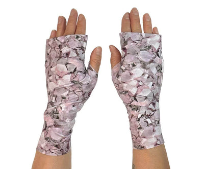 Heliades UPF 50 Sun Protective Clothing UV sun gloves on printed fabric. Shown is fashionable, elegant allover pink, lavender, white, magenta print. UV sun covered hands shown front