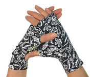 Heliades UPF 50 Sun Protective Clothing UV sun gloves on print fabric. Shown is fashionable, elegant allover navy blue, white floral pattern. UV sun covered hands shown clasped together with bright green logo trim