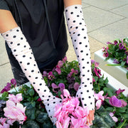UPF50 sun protective arm sleeves fingerless UV driving gloves in ballet pink with black polka dot print holding pink flowers