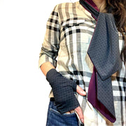 Woman wearing Burberry check shirt and jeans. A hand rests on jeans pants pocket. On hand is best UPF 50+ sun protective fingerless sun gloves in Charcoal Gray repeating rosette print made of UPF50+ and OEKO-TEX certified fabric. HELIADES logo shown, Made in USA. Around neck is UPF50+ reversible scarf, one side is charcoal gray repeating rosette print, the other side is solid color eggplant.