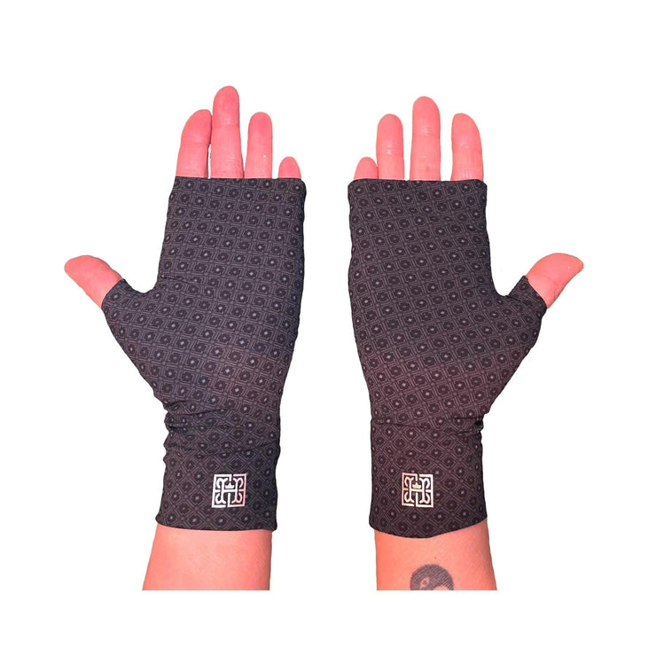 Two hands wearing best UPF 50+ sun protective fingerless sun gloves in charcoal gray repeating rosette pattern made of UPF50+ and OEKO-TEX certified fabric. HELIADES logo shown, Made in USA.
